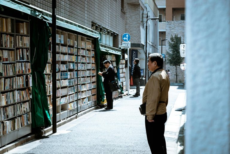A bustling urban street with people browsing outdoor book displays, providing a unique shopping experience.