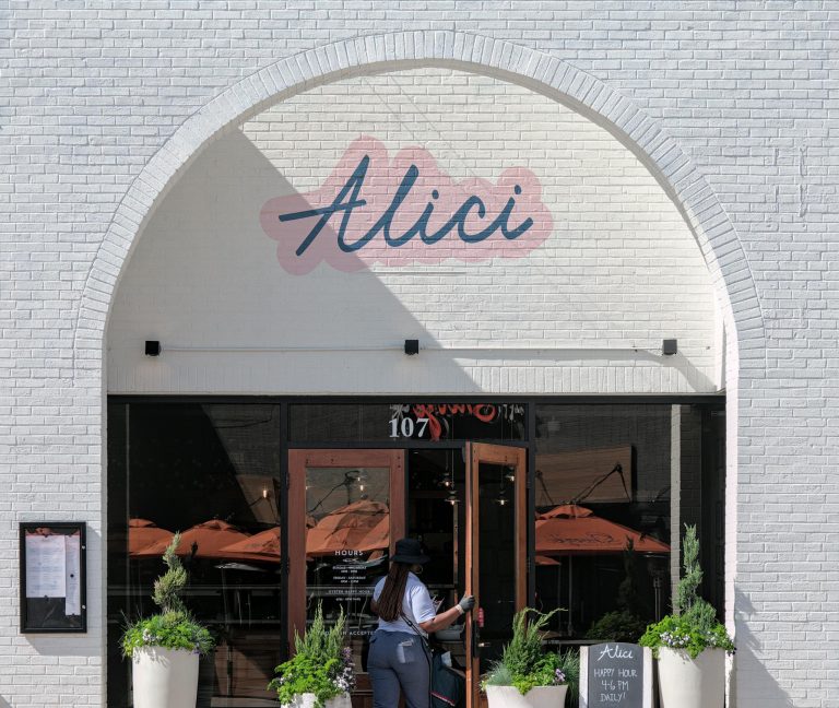 Elegant restaurant exterior in Atlanta featuring entrance with potted plants and signage.